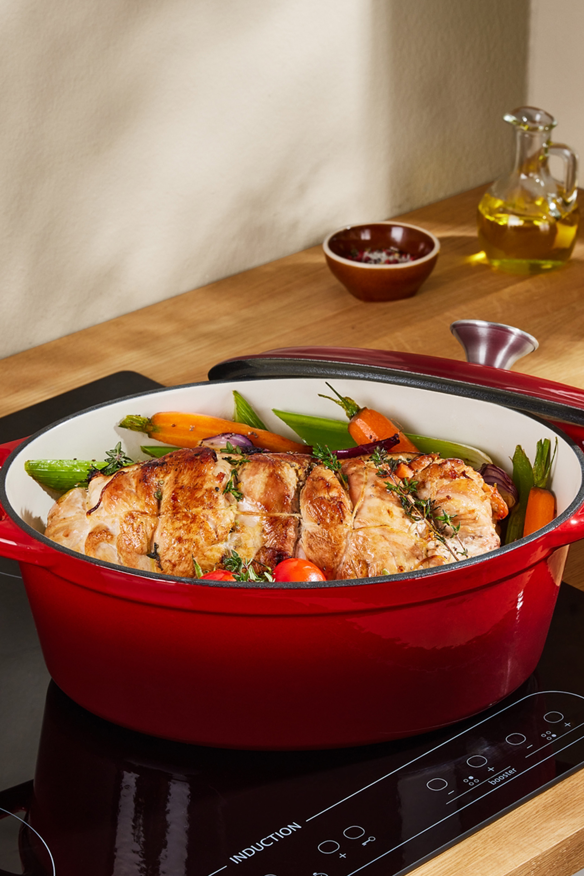 Punane malmpott küpsetatud liha ja köögiviljadega induktsioonpliidil.