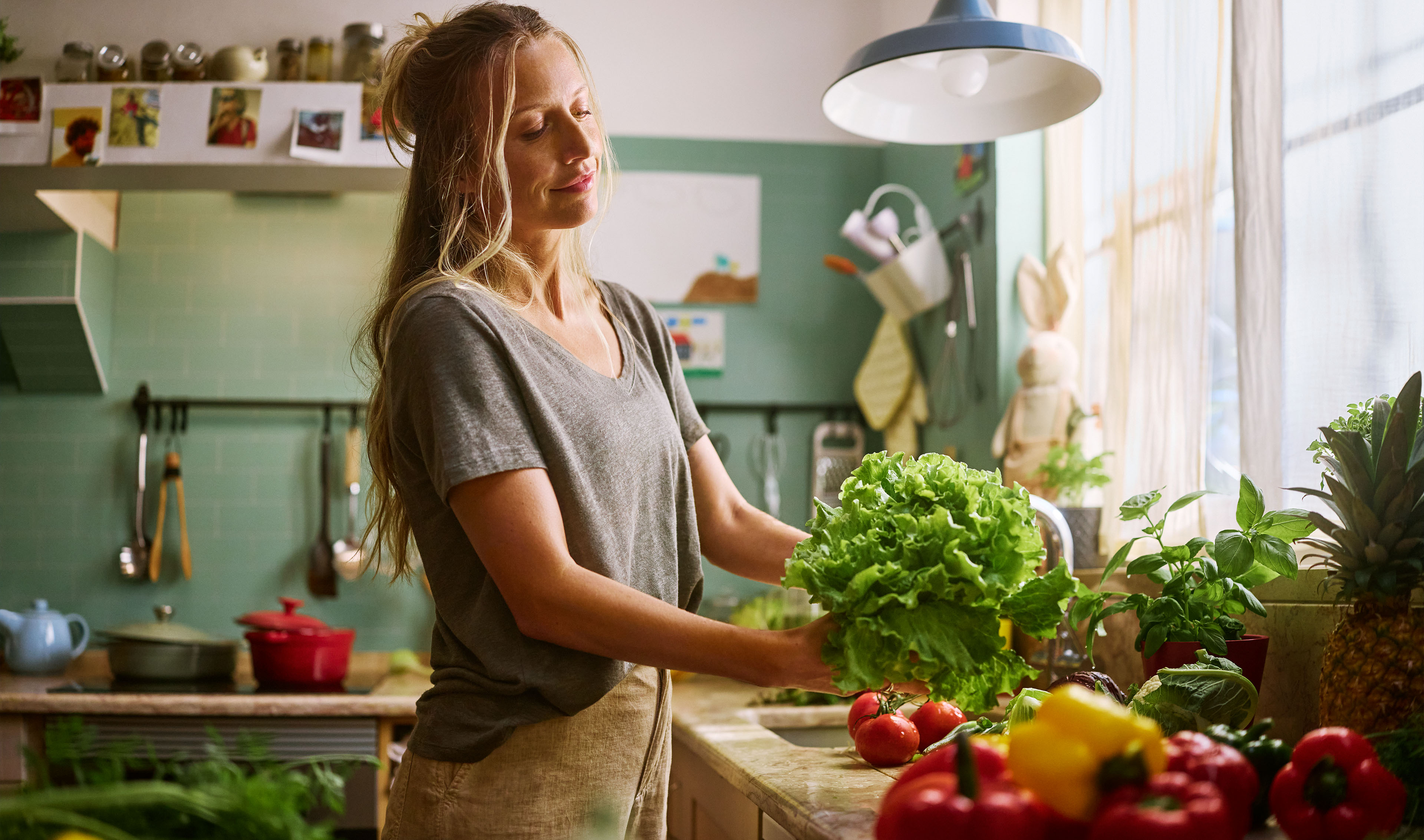 Naine valmistab köögis salatit ja köögivilju.
